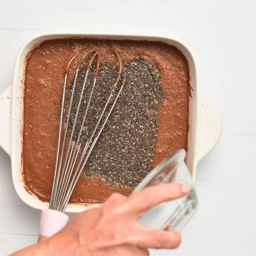 Pouring chia seeds on the base Chocolate Chia Pudding batter.