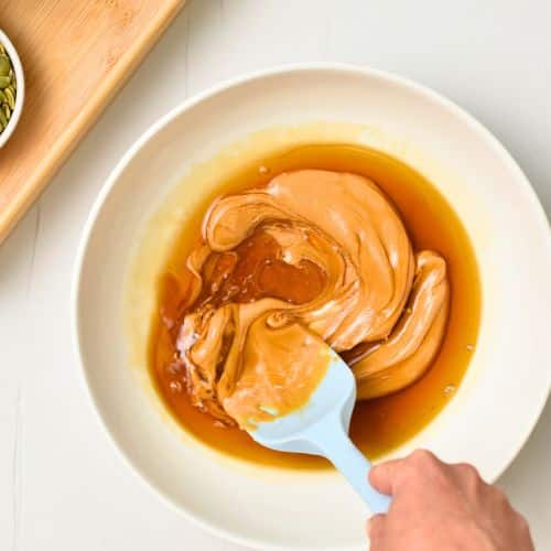 Mixing peanut butter and maple syrup in a bowl.