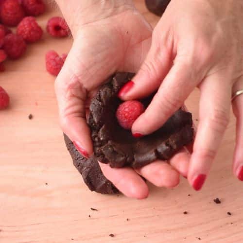 Placing a raspberry in the No-Bake Brownie Bite mixture.