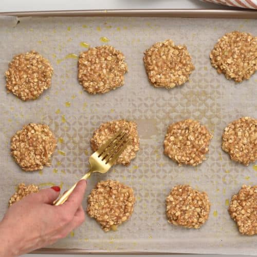 Flattening 2-Ingredient Oat Cookies on a baking sheet.