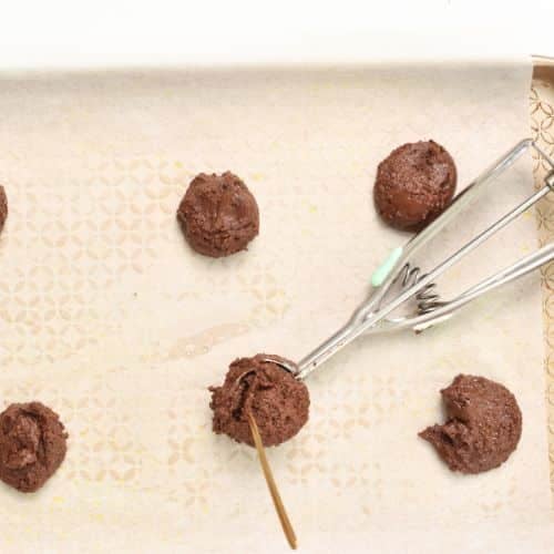 Placing 3-Ingredient Chocolate Cookie dough balls on a baking sheet.