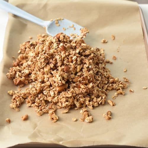 Spreading Banana Granola onto a baking sheet.