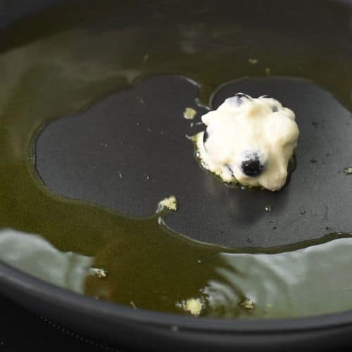 Placing Blueberry Fritters in a pan with oil.