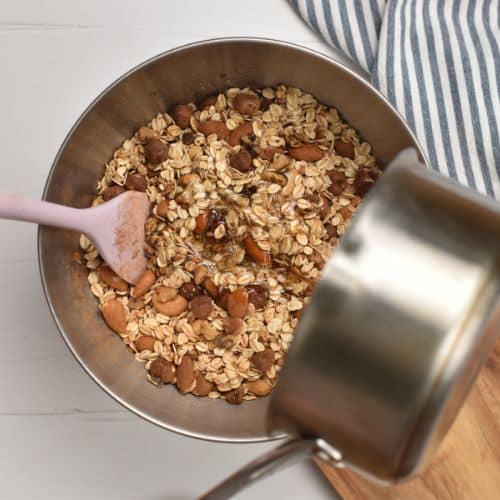 Pouring the maple syrup on the dry Healthy Homemade Granola ingredients.